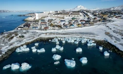 Des icebergs flottant dans les eaux avec des bâtiments en arrière-plan au large de Nuuk, au Groenland, le 11 mars 2025, le jour des élections législatives au Groenland, territoire autonome danois