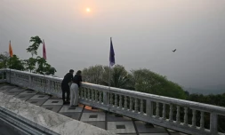 Des touristes face à une vue sur Chiang Mai, obscurcie par la pollution, depuis le sommet du temple Wat Phra That Doi, le 15 mars 2024 en Thaïlande