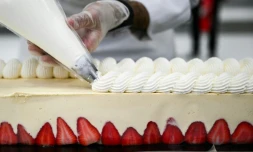 Un pâtissier travaille sur le plus grand fraisier du monde, d'une longueur de 121,88 m, à Argenteuil, le 23 avril 2025