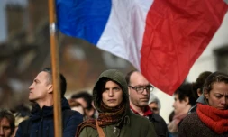 Des passants tiennent le drapeau français le 16 novembre 2015 pendant la minute de silence devant le Carillon, cible des attaques