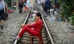 Une Vietnamienne assise sur une chaise posés sur les rails du chemin de fer dans le vieux quartier de Hanoï le 20 octobre 2018.