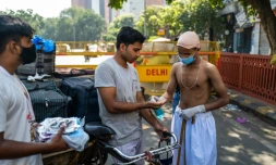 Des bénévoles, dont un habillé comme le héros de l'indépendance indienne, le Mahatma Gandhi, dont c'est l'anniversaire, distribuent des masques aux conducteurs de vélos-taxis, à New Delhi le 2 octobre 2020
