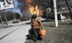 Un homme fuit son quartier aprĂšs des tirs d'artillerie Ă Kharkiv, dans le nord-est de l'Ukraine, le 25 mars 2022