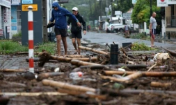 Des piétons au milieu des débris à Saint-Paul de la Réunion après le passage du cyclone Garance le 28 février 2025