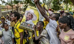 De jeunes partisans du président ougandais sortant Yoweri Museveni brandissent des affiches électorales et chantent des slogans à son dernier meeting de campagne, le 13 janvier 2026 à Kampala