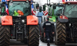 Un policier marche prÚs de tracteurs bloquant l'autoroute A6, le 1er février 2024 prÚs de Chilly-Mazarin en Essonne