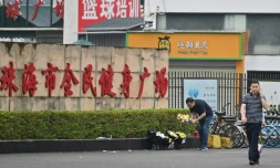 Des employés enlÚvent des fleurs d'un lieu d'hommage improvisé devant le centre sportif de Zhuhai, deux jours aprÚs une attaque meurtriÚre à la voiture-bélier, le 13 novembre 2024 dans la province du Guangdong, dans le sud de la Chine