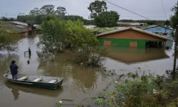 Un homme dans une barque se tient devant une maison inondée à Canoas, dans le sud du Brésil, le 13 mai 2024