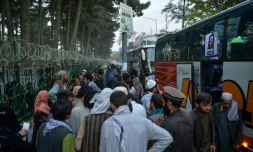 Des déplacés afghans installés dans un campement de fortune à Kaboul s'apprêtent  à monter dans un car pour retourner chez eux, le 29 septembre 2021