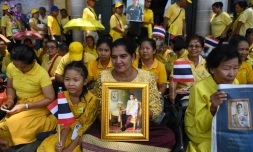 Des ThaĂŻlandaises tiennent le portrait du roi Maha Vajiralongkorn, prĂšs du Grand palais, en attendant la grande parade pour son couronnement dans les rues de Bangkok, le 5 mai 2019