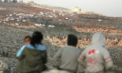 Des enfants syriens observent les alentours depuis un camp de fortune pour les déplacés ayant fui les attaques des forces pro-régime dans les provinces d'Idleb et Alep, près de la frontière turque le 18 février 2020