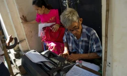 Aung Min, un des rares écrivains publics restant dans la capitale birmane Rangoun, travaille sur le document d'une cliente dans la rue Pansodan, le 5 décembre 2018