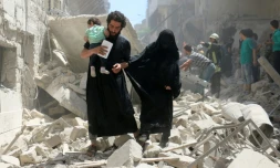 Une famille parmi les décombres d'habitations bombardées dans une zone détenue par les rebelles à Alep, le 28 avril 2016