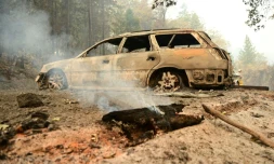 Un morceau de bois fume devant une voiture brûlée dans une propriété lors d'un incendie dans le comté de Shasta, au sud de Lakehead, en Californie, 2 juillet 2021
