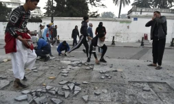 Des manifestants brisent des pavés à Alger tandis que la police fait usage de gaz lacrymogène, le 22 février 2019