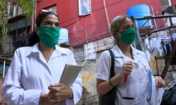 Liz Caballero Gonzalez (g), médecin, et l'étudiante en médecine Susana Diaz font du porte à porte dans le quartier du Vedado, le 31 mars 2020 à La Havane, pendant l'épidémie de coronavirus à Cuba