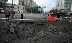 Des habitants de Kiev passent prÚs d'un cratÚre causé par une frappe de missile russe sur la capitale de l'Ukraine, le 11 juillet 2026