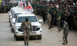 Des combattants du Hamas escortent un convoi de la Croix-Rouge arrivant à Nousseirat, dans la bande de Gaza, pour récupérer trois otages israliens le 22 février 2025