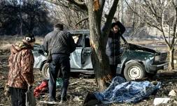 Des habitants prÚs du corps d'un homme tué dans un bombardement, le 24 février 2022 à Tchouhouïv, dans l'est de l'Ukraine