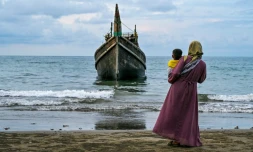 Une femme et son enfant devant l'embarcation qui a transporté des centaines de réfugiés Rohingyas jusqu'à la
plage de Laweueng, en IndonĂ©sie, oĂč ils ont accostĂ© aprĂšs avoir fui les camps du Bangladesh, le 10 dĂ©cembre 2023