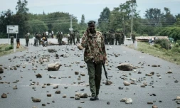 Un policier kényan marche sur une route couverte de pierres érigées en barricades par des partisans de l'opposition à Ahero, à environ 25 km à l'est de Kisumu, le 26 octobre 2017