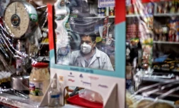 Un commerçant attend le client derriÚre une cloison en nylon pour se protéger du coronavirus sur le marché d'Iztapalapa, à Mexico le 22 juin 2020