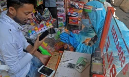 Un bénévole demande à un vendeur de porter un masque dans son échoppe pour lutter la diffusion du Covid-19, le 23 avril 2021 à Siliguri, en Inde