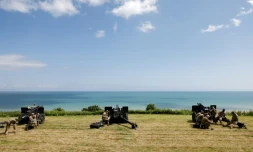 Des militaires américains se rassemblent prÚs de canons d'artillerie de campagne surplombant la plage d'Omaha et la Manche, prÚs du cimetiÚre américain de Colleville-sur-Mer, dans le nord-ouest de la France, le 5 juin 2024