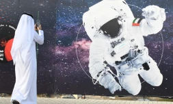 Un passant photographie l'image d'un astronaute dont le vĂȘtement porte le drapeau Ă©mirati, devant le centre spatial Mohammed Bin Rashid Ă DubaĂŻ, le 25 septembre 2019