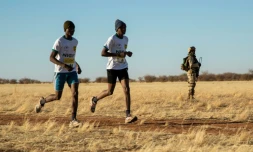 Deux marathoniens passent devant un soldat lors du premier marathon jamais organisé au Niger, le 29 décembre à Agadez.