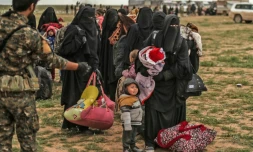 Un combattant des Forces démocratiques syriennes surveille des personnes évacuées du dernier réduit du groupe Etat islamique à Baghouz, dans l'est syrien, le 27 février 2019 