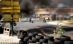 Militants de l'Union générale des travailleurs de Guadeloupe, faisant rouler des pneus pour installer un barrage à Perrin Les Abymes, en Guadeloupe, le 17 novembre 2021