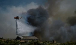 Un hélicoptère largue une cargaison d'eau sur un feu de forêt à Keratea, près d'Athènes, le 30 juin 2024 en Grèce