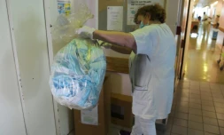 Une infirmiÚre récupÚre un sac plastique contenant des masques chirurgicaux à recycler, le 10 avril 2021 à l'hÎpital Saint-Antoine, à Paris