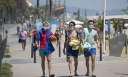 Des promeneurs avec les masques le long de la plage à Barcelone, le 18 juillet 2020