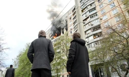 Des passants observent l'incendie provoqué par une frappe dans un appartement des faubourgs nord de Kharkiv, dans l'est de l'Ukraine, le 22 avril 2022