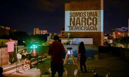 Des membres de "la nouvelle bande de la terrasse" projettent un slogan sur le mur d'un immeuble, le 9 août 2020 à Medellin, en Colombie