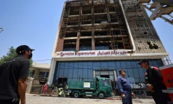 Opération de nettoyage devant le bâtiment du centre commercial Hyper Mall ravagé par un incendie dans la nuit tuant plus de 60 personnes, le 17 juillet 2025 à Kut, dans l'est de l'Irak
