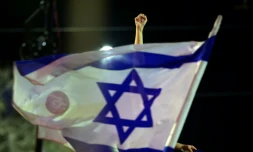 Un manifestant lève le poing derrière un drapeau israélien lors d'une manifestation anti-gouvernementale près de la résidence du Premier ministre israélien à Jérusalem, le 20 mars 2021, avant les législatives du 23
