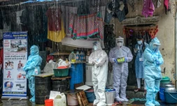 Des soignants en combinaison de protection s'abritent de la pluie à Bombay (Inde) le 12 août 2020