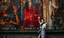 Une femme pose devant des affiches de la série télévisée chinoise "Blossoms Shanghai" du réalisateur hongkongais Wong Kar-wai, le 7 janvier 2024 à Shanghai