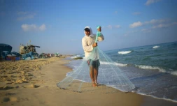 Le pêcheur palestinien Jihad al-Soltan se prépare à lancer son filet de pêche sur la plage de Beit Lahia à Gaza, le 22 août 2017