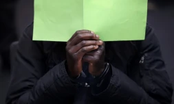 L'accusé gambien Bai L. se cache derriÚre un dossier pendant qu'il est assis dans la salle d'audience, le 25 avril 2022 à Celle, dans le nord de l'Allemagne, lors de l'ouverture de son procÚs