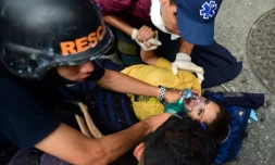 Des secouristes viennent en aide à une femme blessée lors des manifestations à Caracas le 20 avril 2017