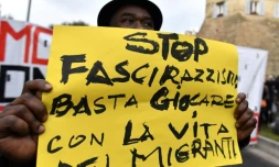 Un manifestant tient une banderolle sur laquelle on peut lire "stop au fascisme et au racisme, arrĂȘtez de jouer avec la vie des migrants", lors d'une manifestation antifasciste Ă Macerata, en Italie, le 10 fĂ©vier 2018.