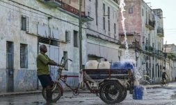 Un homme remplit des récipients d'eau à un point de ravitaillement public dans une rue de La Havane, le 5 octobre 2026