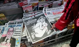 Une femme regarde dans un kiosque, le 6 janvier 2016 à Paris, le numéro spécial de Charlie Hebdo paru un an après l'attentat