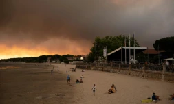 Des touristes sur la plage d'Andernos-Les Bains prĂšs de LĂšge Cap-Ferret oĂč sĂ©vit un important incendie, le 23 juillet 2026