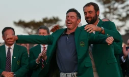 Le Nord-irlandais Rory McIlroy enfile la fameuse veste verte dévolue au vainqueur du Masters de golf d'Augusta, aux Etats-Unis, que lui remet le précédent tenant du titre Scottie Scheffler, le 13 avril 2025