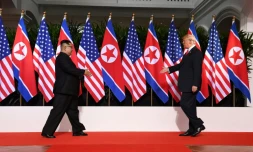 Le leader nord-coréen Kim Jong Un (g) et le président américain Donald Trump se dirigent l'un vers l'autre pour se serrer la main, le 12 juin 2018 à l'hôtel Capella sur l'île de Sentosa, à Singapour